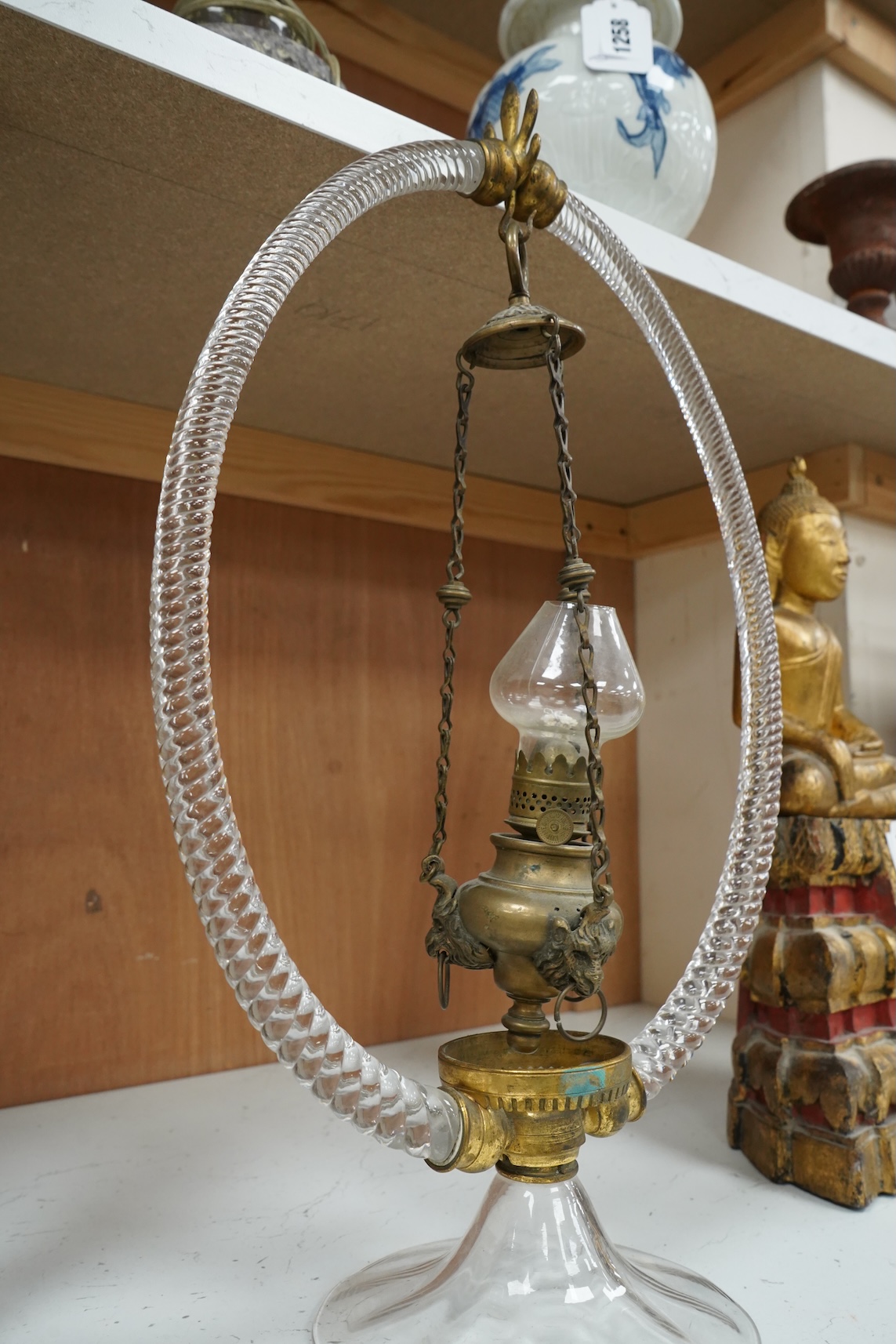 A Victorian glass frame with a central brass hanging oil lamp. 48cm high